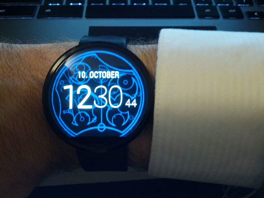 A circular smartwatch has a glowing circular Gallifreyan background.