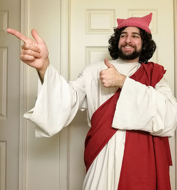 Jesus wears a pink hat and poses like the Buddy Christ statue.