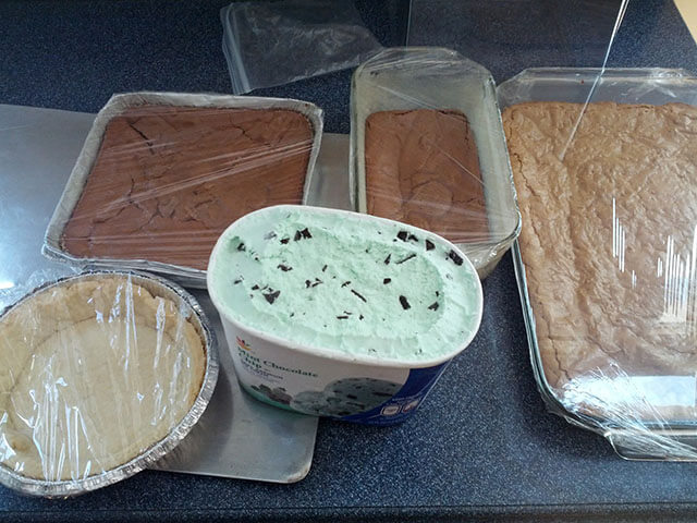 Baked tart crust, brownies, and blondies, next to a tub of mint chocolate chip ice cream.