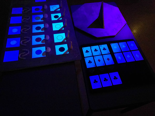Under a blacklight, dots are visible in the third row of android parts, and the blue playing cards have suits.