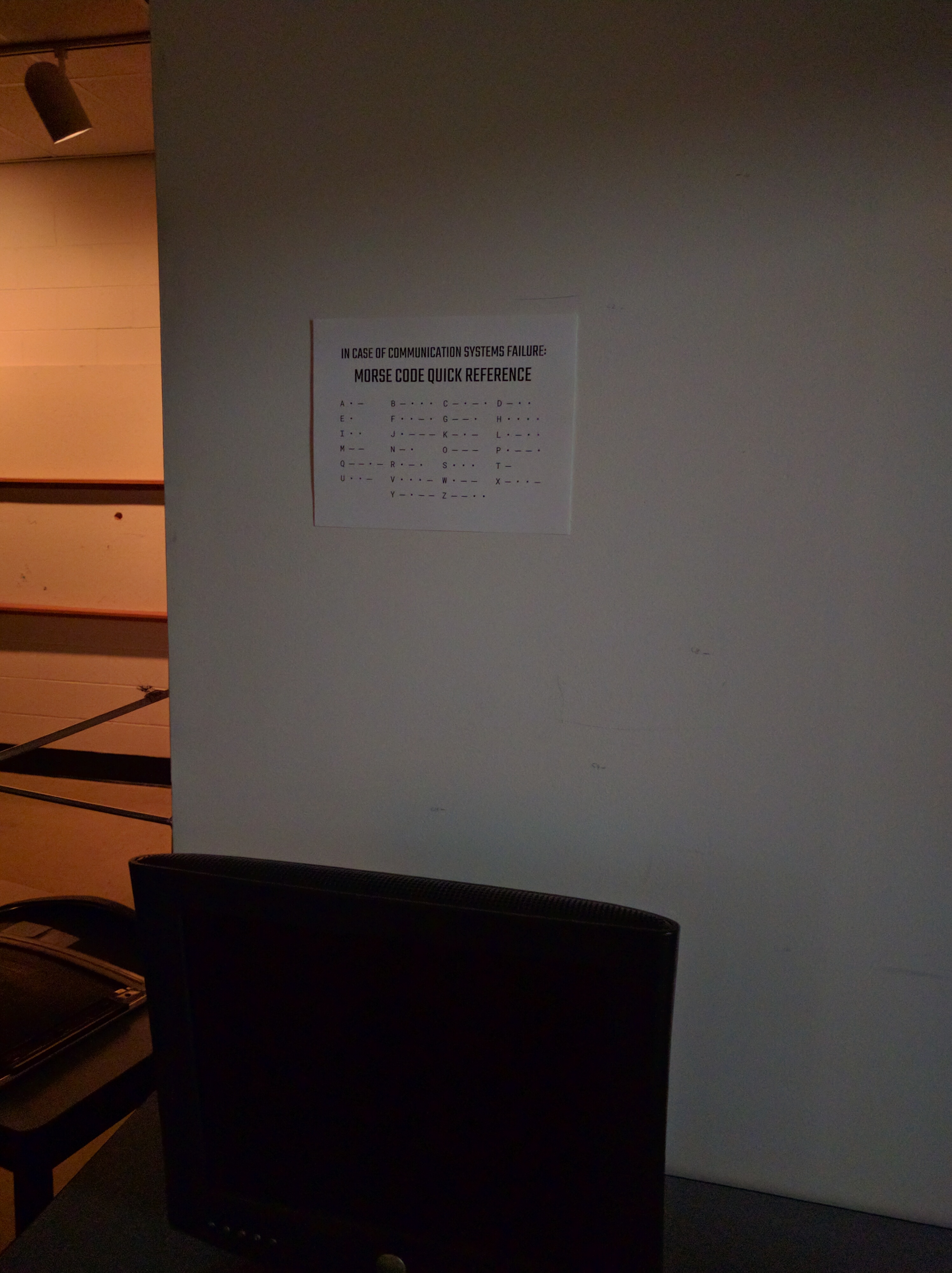 A sign on the wall says, In case of communication systems failure: Morse code quick reference, followed by the Morse code alphabet.