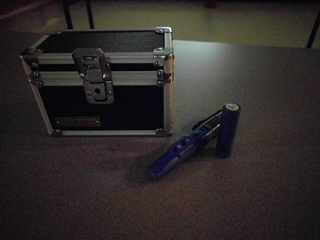 A lock box sits on a table with a pole checker and a battery.