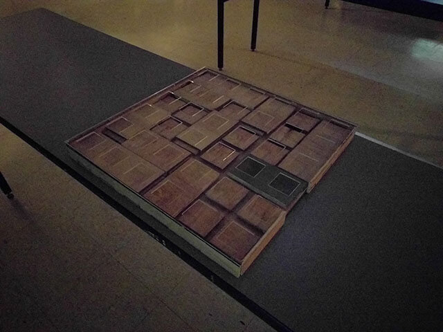 A sliding block puzzle has a clear plastic grid over it to prevent the pieces being removed except through the exit opening.